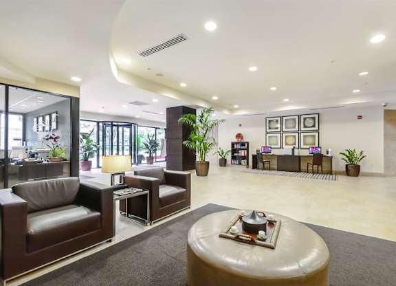 A modern living room with a brown leather couch and a round ottoman.