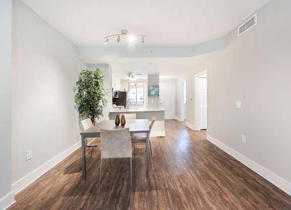 A dining room with a table and chairs and a potted plant.