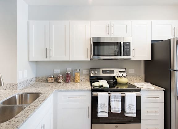 A kitchen with white cabinets and a black refrigerator.