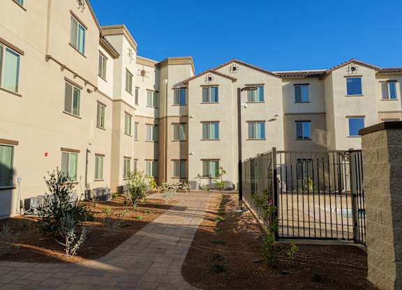 A row of modern apartment buildings with a black fence in front.