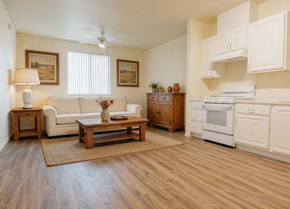 A living room with a couch, a coffee table, and a kitchen area with white appliances.