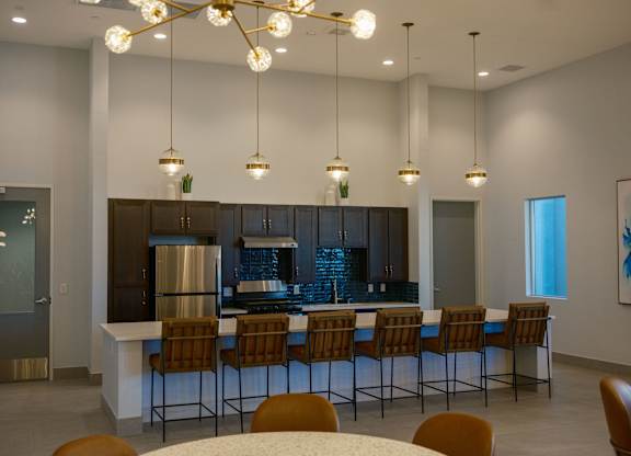 A modern kitchen with a bar area and chairs around it.