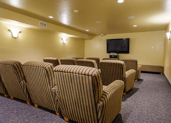 A row of striped chairs are arranged in front of a television in a room.