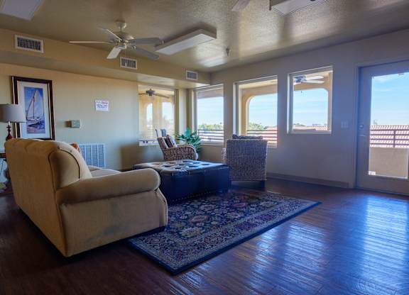 A living room with a beige couch, a rug, and a ceiling fan.