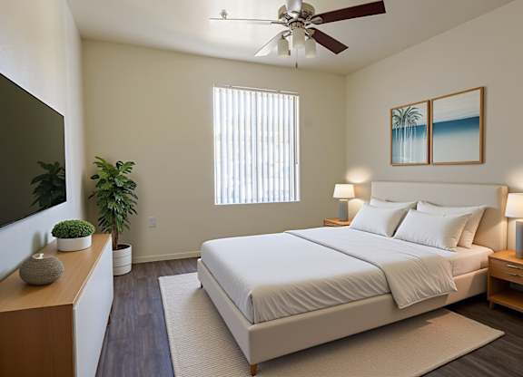A bedroom with a large bed, a ceiling fan, and a painting of a beach scene on the wall.