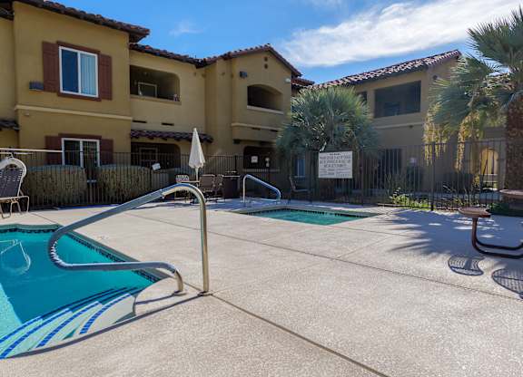 A pool surrounded by a fence and a building in the background.