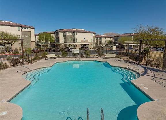 A swimming pool in a residential area with apartment buildings in the background.