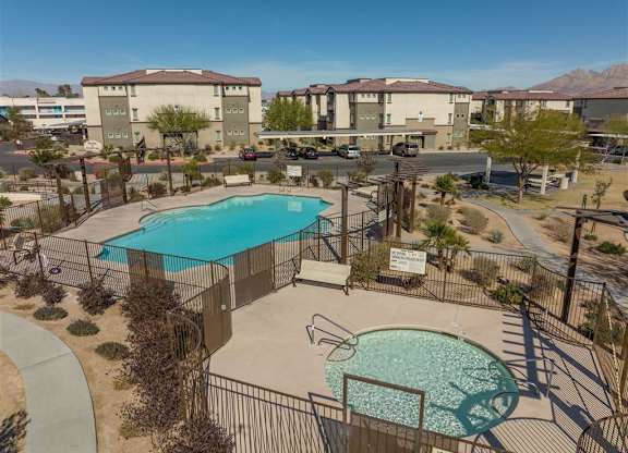 A pool surrounded by a fence and a sign in front of apartment buildings.