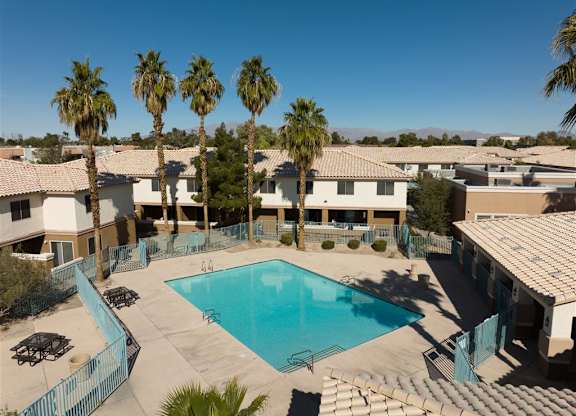 A swimming pool surrounded by palm trees and buildings.