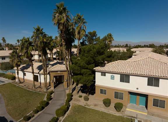 A building with a blue door is surrounded by palm trees.