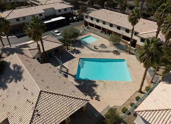 A swimming pool surrounded by palm trees and apartment buildings.