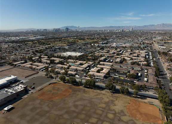 A cityscape with buildings and a baseball field in the foreground.