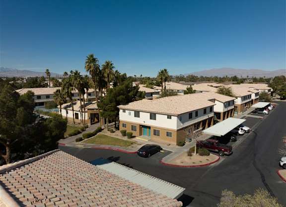 A sunny day at a residential complex with cars parked in the driveway.