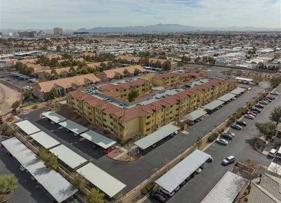A large apartment complex with a parking lot in front.