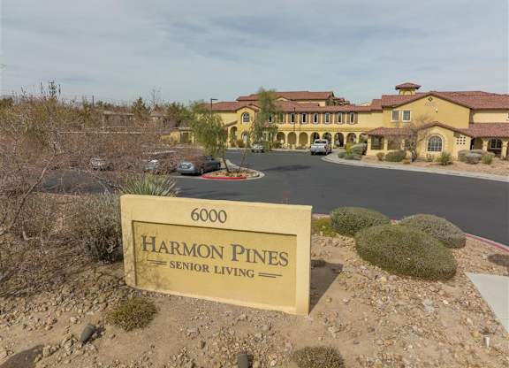 A sign for Harmon Pines Senior Living is in front of a building.