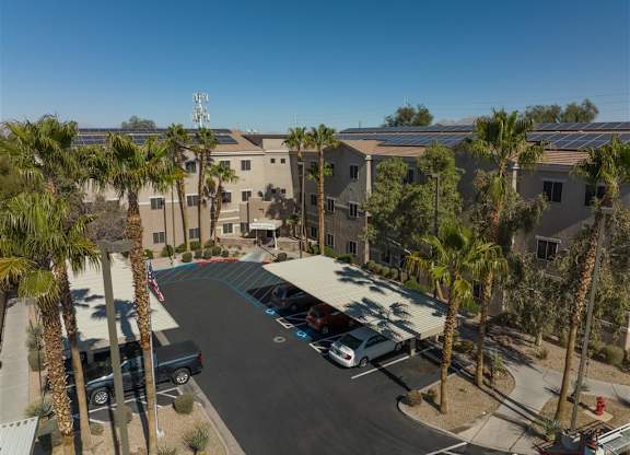 A parking lot with cars and palm trees in front of a building.