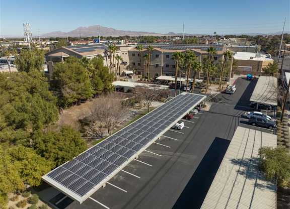 A parking lot with a long row of solar panels on the roof.