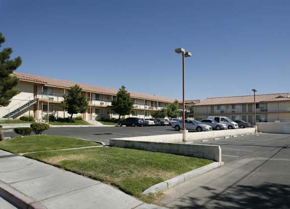 A parking lot in front of a building with cars parked.