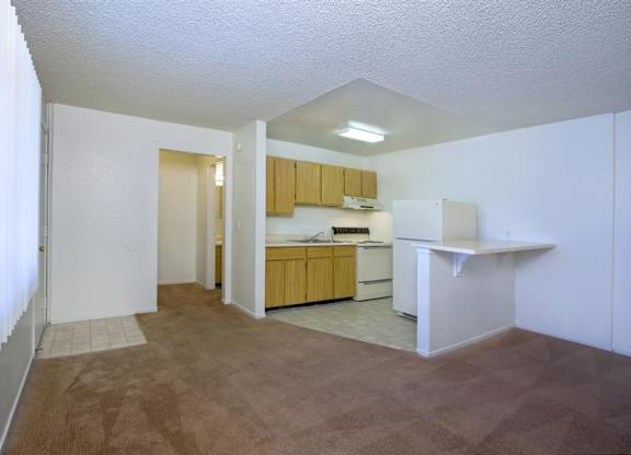 A kitchen area with a white counter and brown carpet.