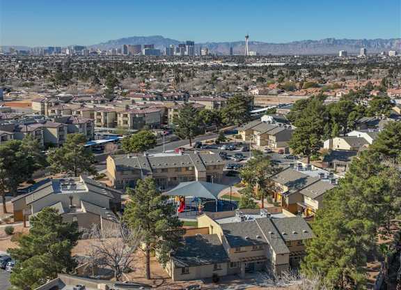 A residential area with houses and trees in the foreground and a city skyline in the background.