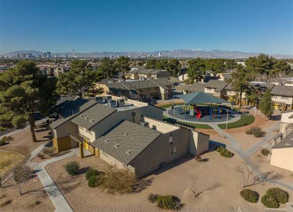 A school building with a playground in the foreground and mountains in the background.