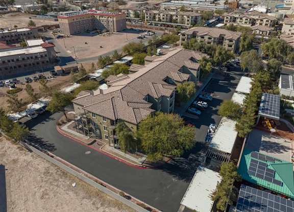 A large building with a red roof is surrounded by other buildings and trees.