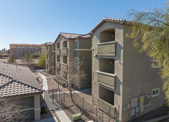 Apartment complex with a black fence and a tree in front.