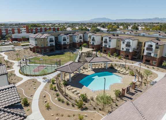 A large swimming pool surrounded by a fence and a gazebo in the middle of a courtyard.