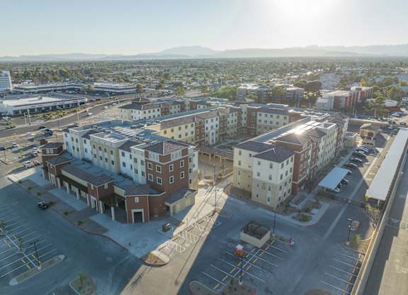 A sunny day in a city with buildings and a parking lot.