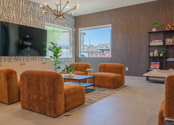 A living room with brown chairs and a large flat screen TV mounted on the wall.