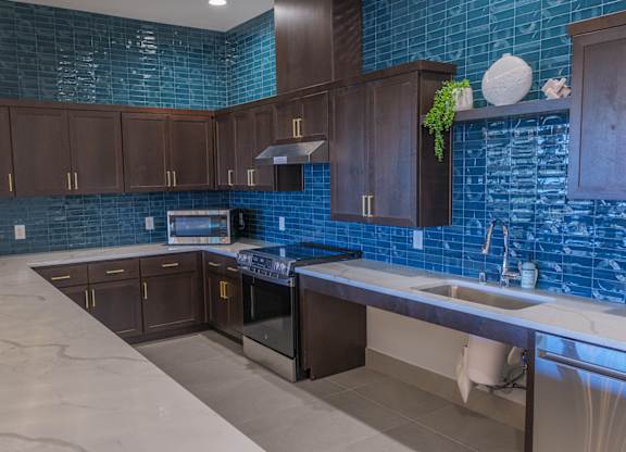 A kitchen with brown cabinets and a blue tile backsplash.