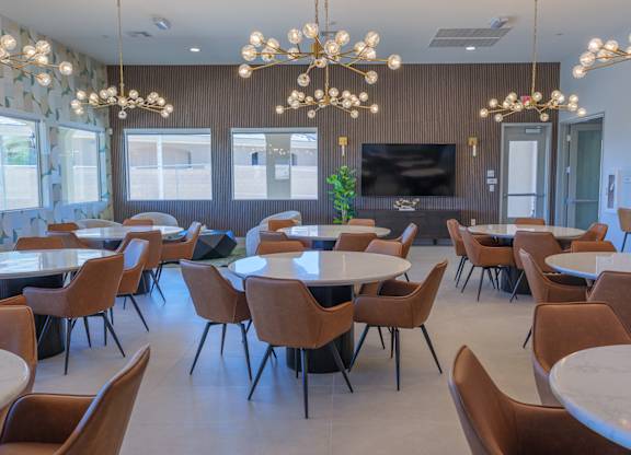 A room with tables and chairs and a chandelier.