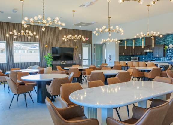 A large room with tables and chairs and a TV.