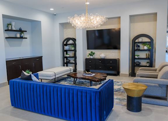 A living room with a blue couch and a chandelier.
