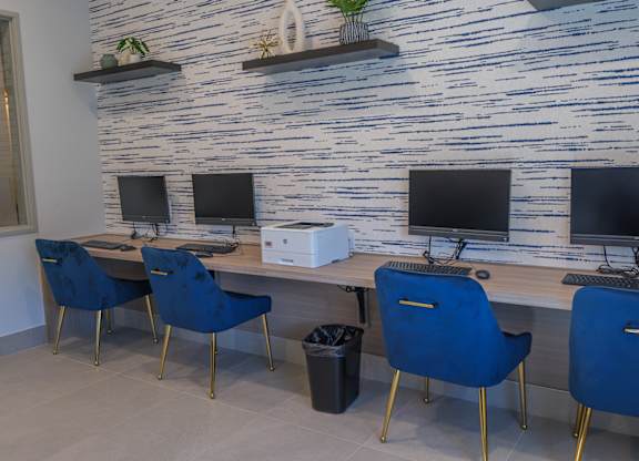 A room with a blue chair and a white desk with a monitor on it.