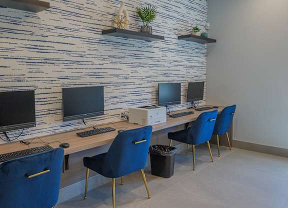A room with a desk, chairs and a computer.