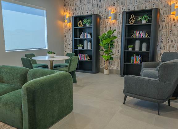 A living room with green chairs and a white table.