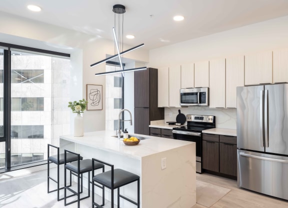 a kitchen with white cabinets and a large white island with black stools at 220 Meridian, Indianapolis, IN 46204