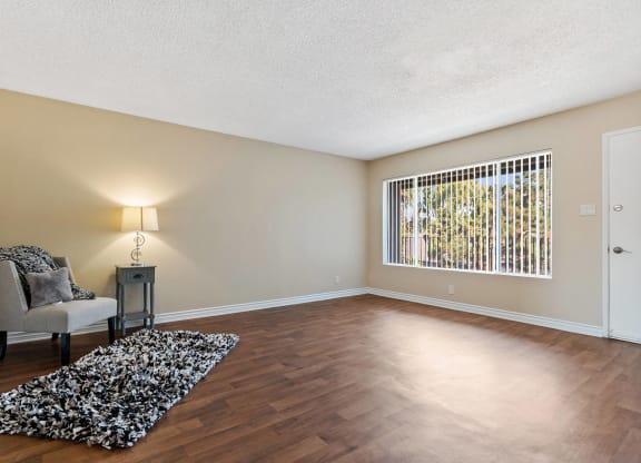 an empty living room with a chair and a rug at Terramonte Apartment Homes, Pomona, CA