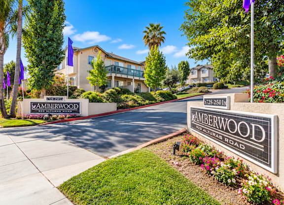 A sign for Amberwood Apartments is displayed in front of a building.