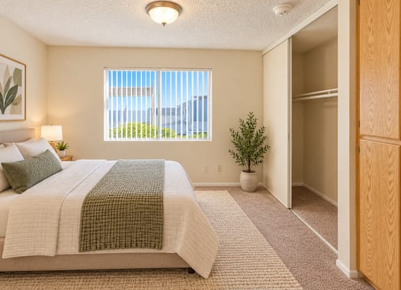 A bedroom with a large bed and a window with blinds.