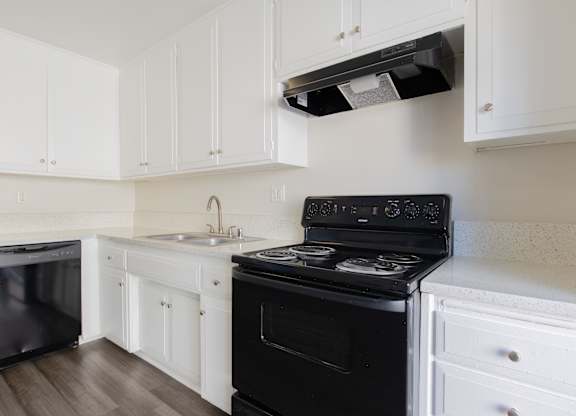 A black stove in a kitchen with white cabinets.