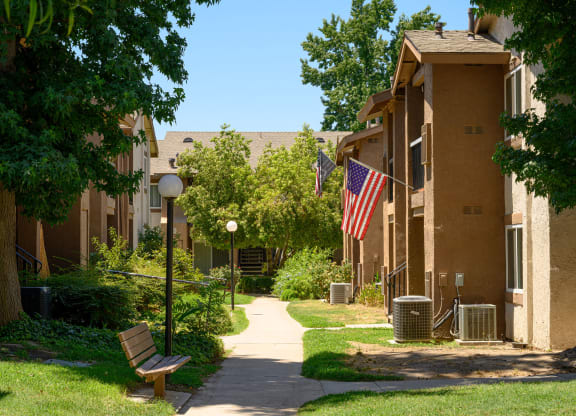 a pathway with a bench and trash cans in front of an apartment building at Oak Terrace Senior Apts, California, 92543