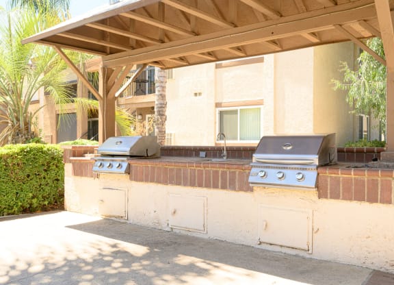 an outdoor kitchen with two grills and a sink at Oak Terrace Senior Apts, Hemet, CA