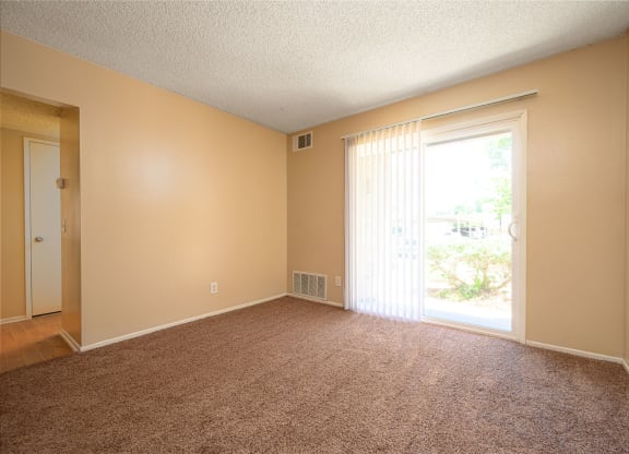 a bedroom with a sliding glass door and a carpeted floor at Oak Terrace Senior Apts, California, 92543