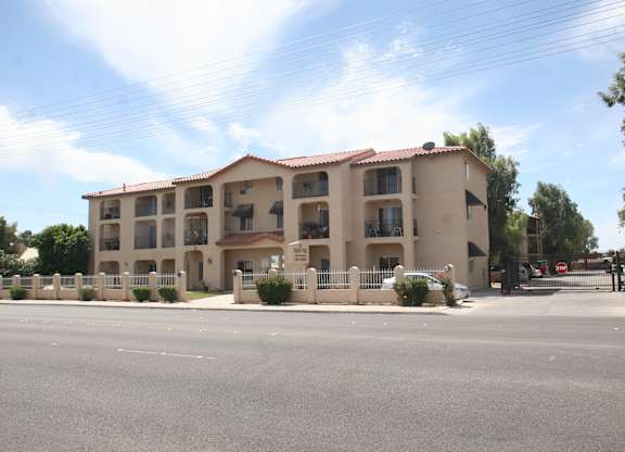 A large apartment building with a parking lot in front.