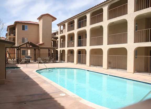 A large swimming pool in front of a building with a balcony.