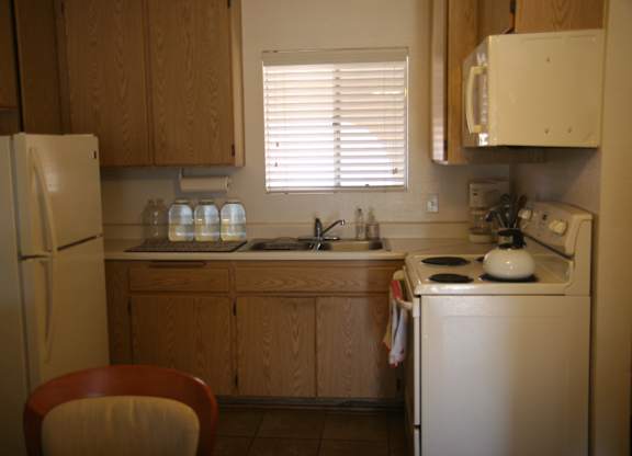 A kitchen with a refrigerator, sink, and stove.