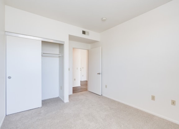 a bedroom with white walls and carpet at Helix at University Village, Pomona California