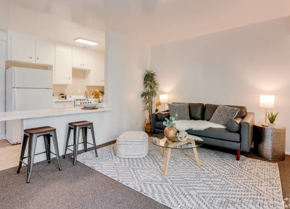 a living room with a couch and a kitchen with a bar and stools at University Park, Azusa, 91702
